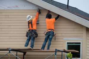 construction workers installing siding and roofing