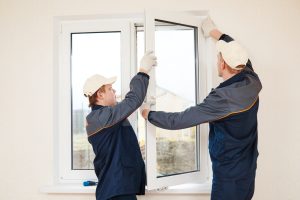two uniformed workers installing windows